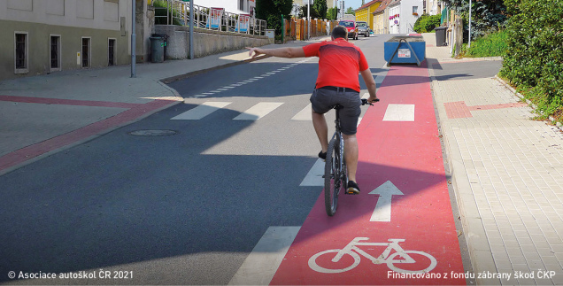 Cyklistovi, který dává znamení o změně směru jízdy proto, aby mohl přejet z vyhrazeného jízdního pruhu pro cyklisty do průběžného pruhu, řidič jedoucí v přilehlém pruhu: